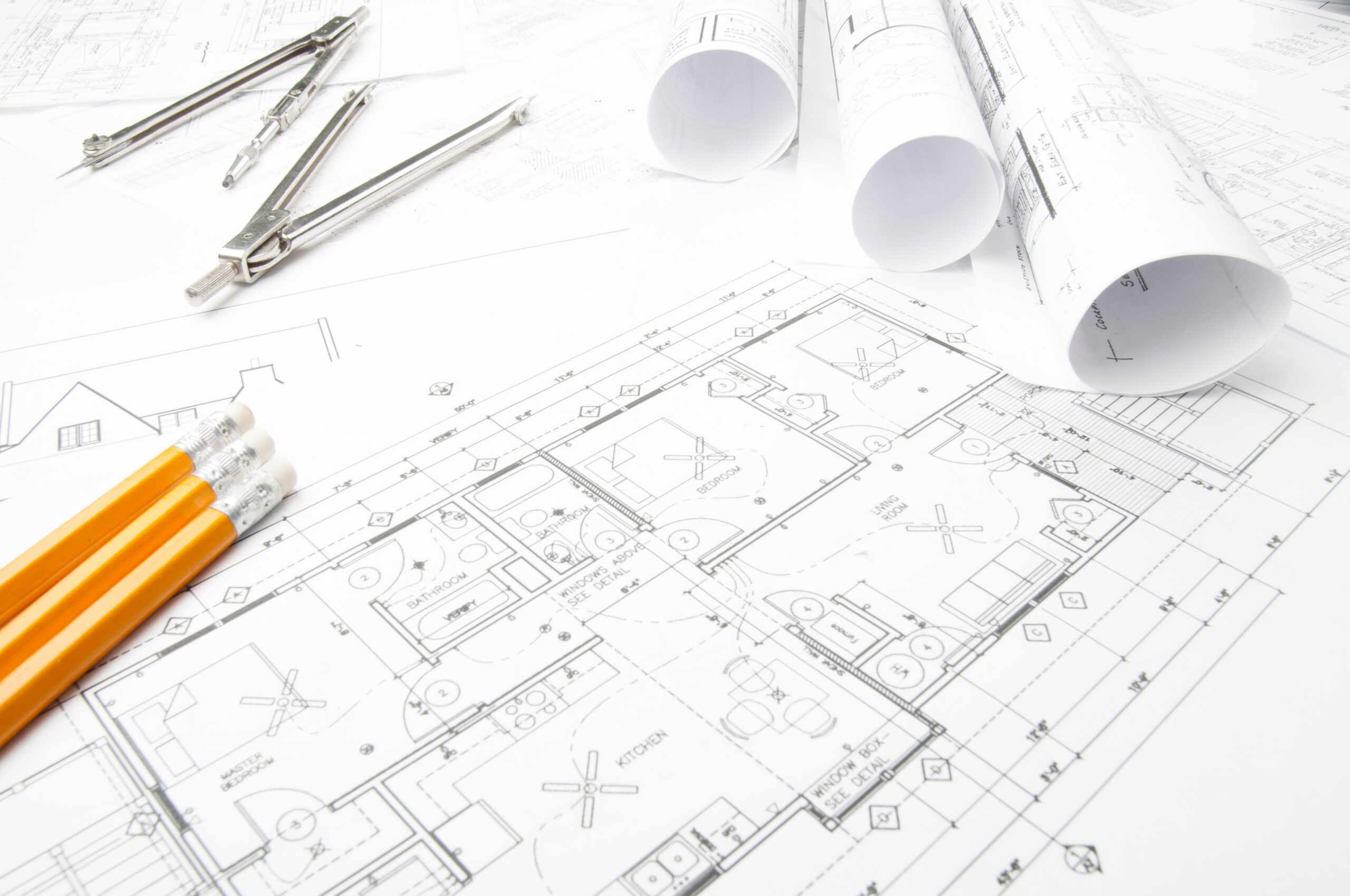 Construction planning drawings on the table and two yellow pencils